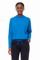Model wearing Annie Light Ponte Hoodie in Sapphire Blue with drawstring hem and cross-front hood.