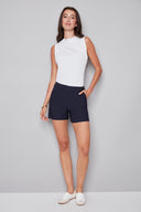 Model wearing the Lisa Techno Short in Navy, featuring a mid-rise pull-on waistband, angled side pockets, and a tailored slim fit, front view.
