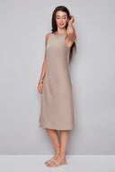 Side view of model wearing the Daphne Belize Satin Sleeveless Dress in Almond, showcasing the sleek sleeveless cut and soft satin drape.