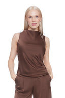 Model wearing the Veronica Belize Satin Sleeveless Top in Brown, featuring a high neckline and sleek satin finish, front view.