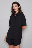 Model wearing the Presley Air Flow Button-Down Top in Black, featuring a slim fit, short sleeves, and classic button-front design, front view.
