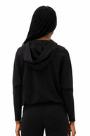Model wearing Annie Light Ponte Hoodie in Black with drawstring hem and cross-front hood.