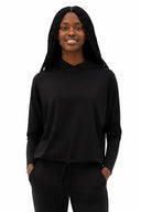 Model wearing Annie Light Ponte Hoodie in Black with drawstring hem and cross-front hood.
