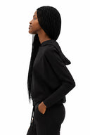 Model wearing Annie Light Ponte Hoodie in Black with drawstring hem and cross-front hood.