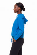 Model wearing Annie Light Ponte Hoodie in Sapphire Blue with drawstring hem and cross-front hood.
