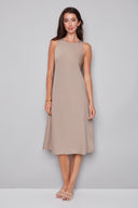 Model wearing the Daphne Belize Satin Sleeveless Dress in Almond, featuring a high crew neckline and flowy A-line silhouette, front view.