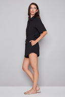 Side view of model wearing the Nora  black Air Flow Lounge Short, showcasing the airy silhouette and higher side hem.