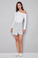 Model wearing the Shira Grey Striped Techno Skort in Grey Stripe, featuring an asymmetric front flap and tailored striped design, front view.