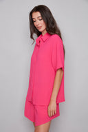 Model wearing the Presley Air Flow Button-Down Top in Raspberry, featuring a slim fit, short sleeves, and classic button-front design, side view.