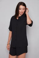 Model wearing the Presley Air Flow Button-Down Top in Black, featuring a slim fit, short sleeves, and classic button-front design, front view.