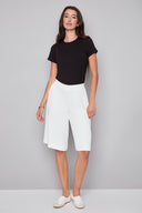 Model wearing the Avery Vegan Silk Bermuda Short in Cream, featuring a mid-rise pull-on waistband, angled side pockets, and a sleek Bermuda-length silhouette, front view.