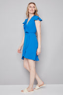 Model wearing the Jessie Vegan Silk Ruffle Dress in Breeze, featuring a flowy silhouette, wrap-inspired neckline, and flounced ruffle details, side view.