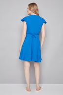 Model wearing the Jessie Vegan Silk Ruffle Dress in Breeze, featuring a flowy silhouette, wrap-inspired neckline, and flounced ruffle details, back view.